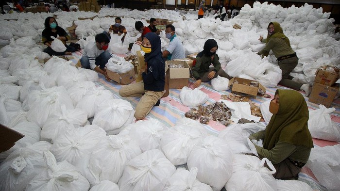 Relawan membungkus paket sembako bantuan dari berbagai perusahaan di Convention Hall, Surabaya, Jawa Timur, Minggu (26/4/2020). Bantuan sembako sebanyak 68.000 paket tersebut akan didistribusikan oleh Pemerintah Kota Surabaya kepada masyarakat berpenghasilan rendah (MBR) di 31 kecamatan yang terdampak COVID-19. ANTARA FOTO/Moch Asim/aww.