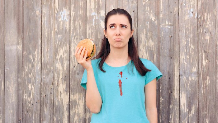 Ilustrasi wanita makan burger berantakan.