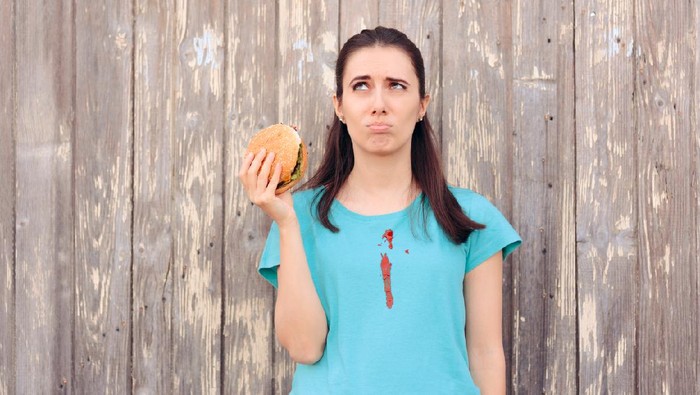 Makan Burger Ilustrasi wanita makan burger berantakan.