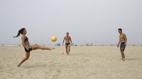 Selain berjemur, sebagian dari mereka juga asyik bermain bola di atas hamparan pasir pantai Huntington. AP Photo/Marcio Jose Sanchez.