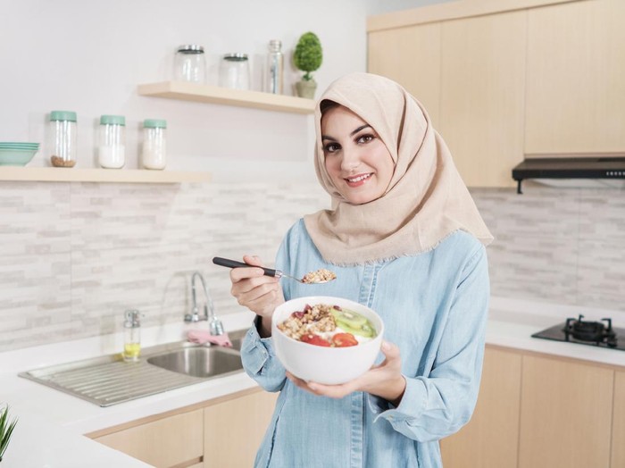 diet saat puasa portrait of beautiful young woman wearing hijab with a bowl of granola with fresh fruit for breakfast