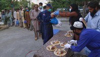 Relawan membagikan makanan gratis kepada pekerja berupah harian dan lainnya untuk berbuka puasa pada hari kedua Ramadhan, di Islamabad, Pakistan. AP/Anjum Naveed