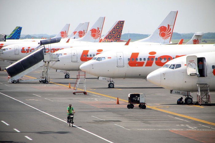 Petugas melintas di sejumlah pesawat yang terparkir di Terminal 1 Bandar Udara Internasional Juanda, Sidoarjo, Jawa Timur, Sabtu (25/4/2020). Kementerian Perhubungan menghentikan sementara aktivitas penerbangan komersil terjadwal baik dalam dan luar negeri untuk mencegah penyebaran virus corona (COVID-19) sebagai pengendalian transportasi selama masa mudik Lebaran 1441 H yang dimulai 24 April hingga 1 Juni 2020. ANTARA FOTO/Umarul Faruq/hp.