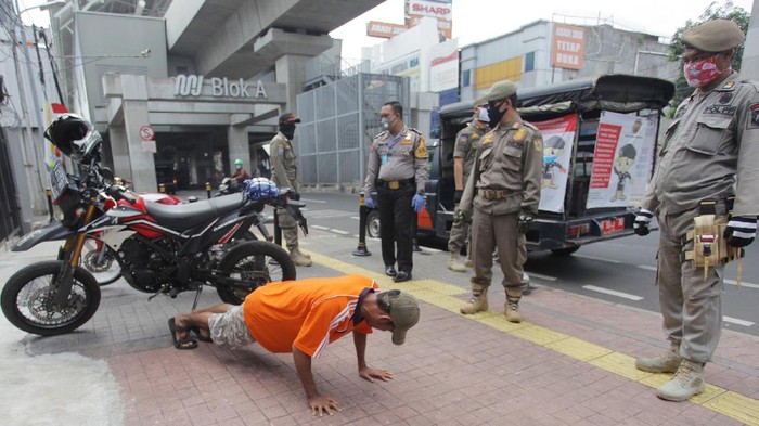 Petugas gabungan memberikan hukuman push up kepada warga yang tidak memakai masker saat razia Pembatasan Sosial Berskala Besar(PSBB) di Kawasan Jalan Fatmawati, Jakarta, Selasa (28/4/2020).  Penertiban tersebut terkait pelaksanaan Pembatasan Sosial Berskala Besar(PSBB) di wilayah Jakarta dan memutus rantai penyebaran COVID 19. ANTARA FOTO/Reno Esnir/foc.