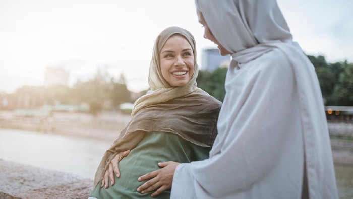 ibu hamil muslim Cute and lovely pregnant Muslim woman and her Muslim friend, spending the time together on a city street.