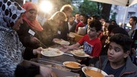 Seorang bocah laki-laki mengambil makanan saat jam buka puasa. Carsten Koall/Getty Images.