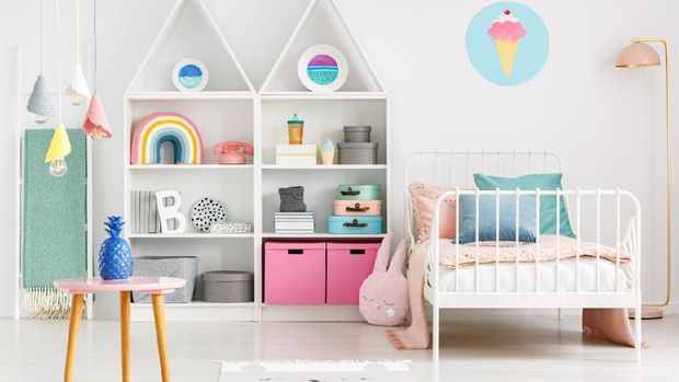 Front view of a kid's room with a table, shelves with boxes and rainbow, single bed and ice cream poster on the wall