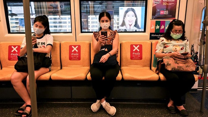 In this photo taken on April 17, 2020 passengers wearing face masks ride a commuter train with chairs marked for social distancing as a preventive measure against the spread of COVID-19 coronavirus in Bangkok. (Photo by Romeo GACAD / AFP)