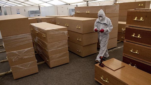 A volunteer walks by coffins at Central Jamia Mosque Ghamkol Sharif in Birmingham, England which is operating a temporary morgue during the Covid-19 pandemic Monday April 20, 2020. The mosque already runs one of the city's oldest Muslim funeral services, and is accepting deceased of all faiths in separate coronavirus and non-coronavirus facilities. (Jacob King/PA via AP)