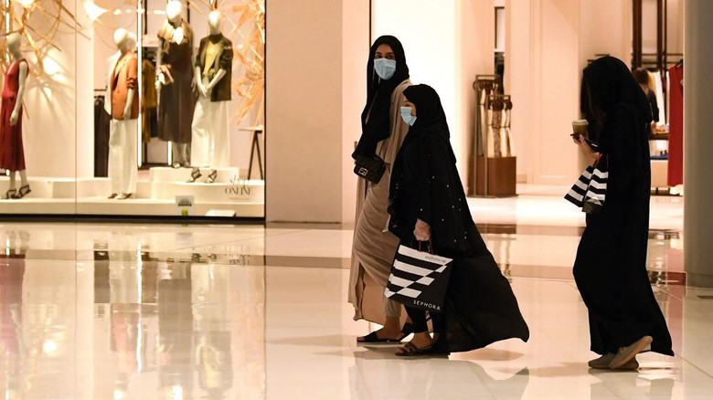 Women wearing masks for protection against the coronavirus, walk in the Mall of Dubai on April 28, 2020, after the shopping centre was reopened as part of moves in the Gulf emirate to ease lockdown restrictions imposed last month to prevent the spread of the COVID-19 illness. (Photo by Karim SAHIB / AFP)