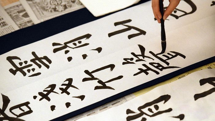 TOKYO, JAPAN - JANUARY 05:  An entrant works on her calligraphy as she takes part in the Kakizome calligraphy contest at the Nihon Budokan on January 5, 2018 in Tokyo, Japan. More than 3000 people participated in this Kakizome contest, where they created their first calligraphy of the new year. The ceremony, which was traditionally performed on the second day of January each year, sees people paint Kanji characters with a writing brush for the first time each year.  (Photo by Carl Court/Getty Images)