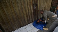 Petugas Satpol PP membangunkan seorang penyandang masalah kesejahteraan sosial (PMKS) yang tidur di emperan toko di Jalan Dewi Sartika, Cawang, Jakarta.