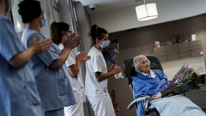 Medical workers clap as Belgian 100 year-old patient Julia Dewilde leaves the Bois de lAbbaye hospital (CHBA) in Seraing, after being succesfully treated for COVID-19, the disease caused by the novel coronavirus, on April 29, 2020. (Photo by Kenzo TRIBOUILLARD / AFP)