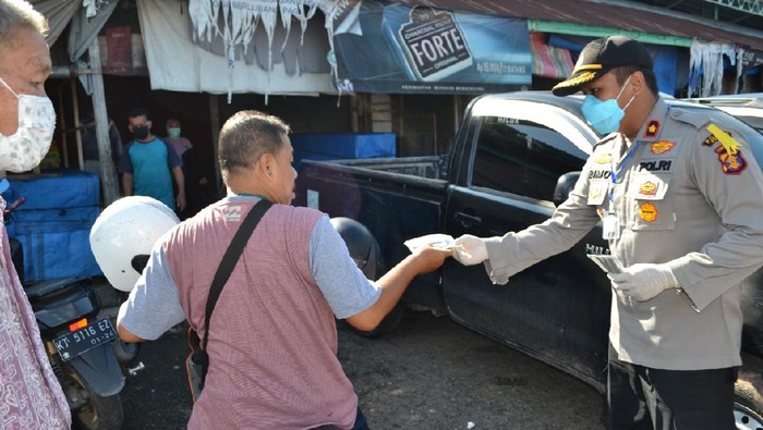 Polisi menjaga pasar tradisional di Paser, Kaltim, untuk memastikan warga dan pedagang memakai masker (dok. Istimewa)