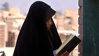 Seorang wanita Irak membaca kitab suci Alquran di Najaf, negara Irak. Marco Di Lauro/Getty Images.