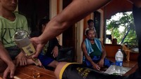Keluarga Balderosdasco menikmati sebotol minuman keras setelah seharian bekerja di lubang lumpur di Paracale, Filipina.