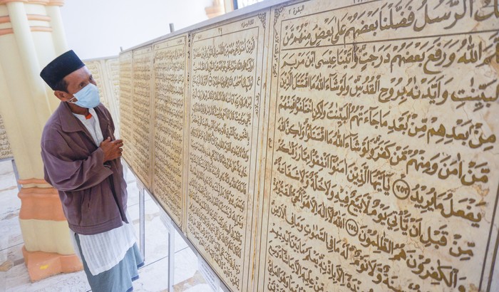 Warga mengamati ukiran Al Quran berbahan batu marmer di Masjid Al Muhtarom, Kabupaten Pekalongan, Jawa Tengah, Kamis (30/4/2020). Huruf Al Quran yang diukir secara manual di batu marmer impor dari Italia yang diukir seniman Indonesia Nurhidayat Sibah itu berjumlah 600 keping berukuran 60x90 centimeter dan tebal dua centimeter dengan berat total sekitar 14 ton. ANTARA FOTO/Harviyan Perdana Putra/aww.