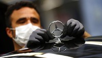 Seorang karyawan memasang logo Mercedes-Benz di kap mobil, Kamis (30/4/2020).