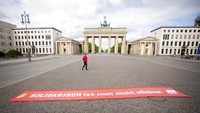  Tak terlihat kerumunan massa di depan Gerbang Brandenburg, Jerman. Hanya sebuah spanduk merah bertuliskan solidarisch ist man nicht allein yang tergeletak di depan gerbang. AP Photo/Emrah Gurel.