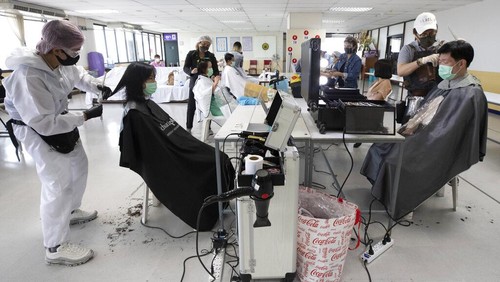 Seorang penata rambut bernama Pornsupa Hattayong bersama sejumlah sukarelawan memberikan layanan potong rambut secara gratis kepada pekerja medis di Rumah Sakit Umum Administrasi Metropolitan Bangkok di Bangkok, Thailand. Foto AP / Sakchai Lalit