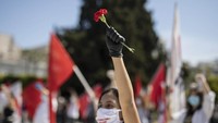  Selain mengibarkan bendera, massa buruh dari serikat PAME juga membawa bunga dalam aksi yang berlangsung di luar Parlemen Yunani tersebut. AP Photo/Petros Giannakouris.