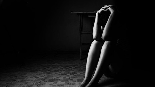 a woman sitting on ground with arm around lower head, sexual violence , sexual abuse, human trafficking concept with shadow edge in white tone