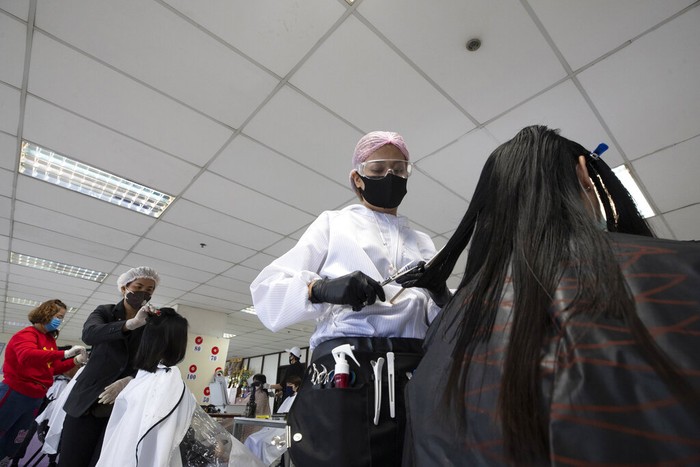 Seorang penata rambut bernama Pornsupa Hattayong bersama sejumlah sukarelawan memberikan layanan potong rambut secara gratis kepada pekerja medis di Rumah Sakit Umum Administrasi Metropolitan Bangkok di Bangkok, Thailand. Foto AP / Sakchai Lalit