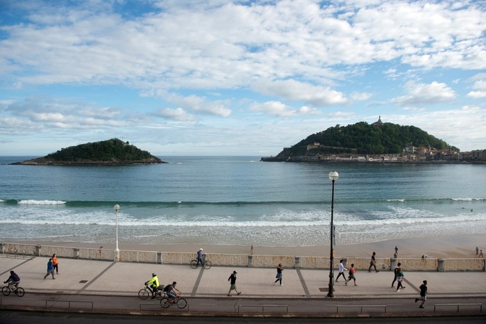 Warga melakukan olahraga di Pantai La Concha di San Sebastian pada 2 Mei  2020 tak lama setelah pemerintah mengizinkan warga keluar rumah untuk kali pertama sejak lockdown nasional untuk memutus rantai COVID-19. Warga diizinkan keluar rumah untuk berolahraga dalam tempo 48 jam sejak 26 April sebagai perpanjangan awal lockdown pada 14 Maret. (Photo by ANDER GILLENEA / AFP)
