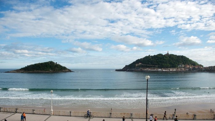 Warga melakukan olahraga di Pantai La Concha di San Sebastian pada 2 Mei  2020 tak lama setelah pemerintah mengizinkan warga keluar rumah untuk kali pertama sejak lockdown nasional untuk memutus rantai COVID-19. Warga diizinkan keluar rumah untuk berolahraga dalam tempo 48 jam sejak 26 April sebagai perpanjangan awal lockdown pada 14 Maret. (Photo by ANDER GILLENEA / AFP)