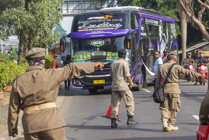Petugas gabungan mengarahkan bus yang membawa pemudik dari arah Bekasi menuju Karawang untuk berputar arah di Perbatasan Karawang - Bekasi, Jawa Barat, Jumat (24/4/2020). Penyekatan akses transportasi di perbatasan tersebut sebagai tindak lanjut kebijakan larangan mudik yang berlaku bagi kendaraan pribadi, angkutan umum dan motor kecuali mobil pemadam kebakaran, angkutan logistik dan kebutuhan pokok serta ambulan. ANTARA FOTO/M Ibnu Chazar/pras.