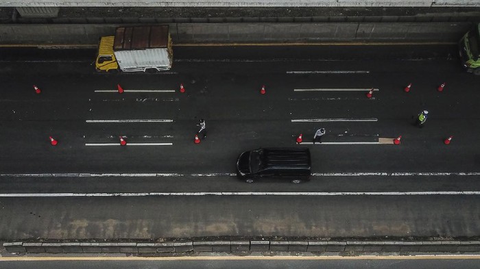Sejumlah polisi menghentikan pengemudi kendaraan yang tidak menerapkan jarak sosial di tol Jakarta-Cikampek, Cikarang, Kabupaten Bekasi, Jawa Barat, Sabtu (25/4/2020). Penyekatan akses transportasi tersebut untuk membatasi pemudik dari Jakarta yang hendak ke luar kota menggunakan mobil pribadi, angkutan umum dan motor. ANTARA FOTO/ Fakhri Hermansyah/hp.