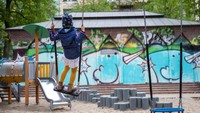Seorang anak asyik menaiki ayunan di taman bermain anak yang kini telah dibuka kembali.