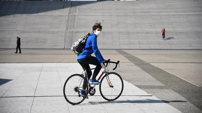 PARIS, FRANCE - MARCH 18: A cyclist wearing a protective mask rides on Esplanade de la Defense the second day after the announcement by French President Emmanuel Macron of the confinement of the French due to an outbreak of coronavirus pandemic (COVID-19) on March 18, 2020 in La Defense, France. From Tuesday, March 17 at noon for at least two weeks, the French will have to stay at home, under penalty of sanctions, unless travel is absolutely necessary, announced the head of state. President launched the war against the coronavirus and placed France in containment without ever saying the word. The Coronavirus epidemic has exceeded 7,900 dead for more than 198,000 infections across the world. (Photo by Pascal Le Segretain/Getty Images )