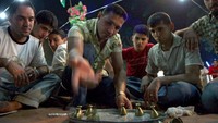 Permainan ini identik dengan tebak menebak siapa yang menyembunyikan cincin pada salah satu anggota timya. Permainan ini sederhana namun menarik dan telah diturunkan dari generasi ke generasi di Irak ketika Ramadhan.  Safin Ahmed/AFP via Getty Images