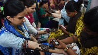 Kios-kios henna biasanya berdekatan dengan toko perhiasan sehingga bisa menarik konsumen yang sedang berbelanja sambil dilukis dengan henna. Selain melakukan tradisi ini, wanita juga membagikan dan bertukar makanan manis. Asif Hassan/AFP via Getty Images