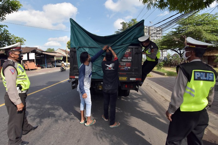 Polisi memeriksa truk barang dalam razia pengamanan dan penyekatan wilayah terdampak COVID-19 di Badung, Bali, Sabtu (2/5/2020). Kegiatan tersebut untuk mengawasi kemungkinan pemudik yang disembunyikan dalam kendaraan angkutan barang menyusul larangan mudik dan penutupan penyeberangan Bali-Jawa karena pandemi COVID-19. ANTARA FOTO/Nyoman Hendra Wibowo/nym/hp.