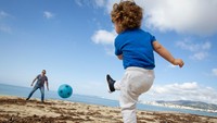 Kebijakan keluar rumah itu lebih dulu diterapkan kepada anak-anak. Seorang anak dan ayahnya bermain di Pantai Can Pere Antoni Beach di Palma de Mallorca, pada 26 April. (AFP/JAIME REINA)