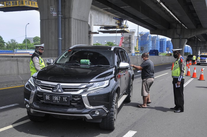 Sejumlah polisi menghentikan pengemudi kendaraan yang tidak menerapkan jarak sosial di tol Jakarta-Cikampek, Cikarang, Kabupaten Bekasi, Jawa Barat, Sabtu (25/4/2020). Penyekatan akses transportasi tersebut untuk membatasi pemudik dari Jakarta yang hendak ke luar kota menggunakan mobil pribadi, angkutan umum dan motor. ANTARA FOTO/ Fakhri Hermansyah/hp.
