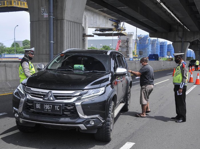 Sejumlah polisi menghentikan pengemudi kendaraan yang tidak menerapkan jarak sosial di tol Jakarta-Cikampek, Cikarang, Kabupaten Bekasi, Jawa Barat, Sabtu (25/4/2020). Penyekatan akses transportasi tersebut untuk membatasi pemudik dari Jakarta yang hendak ke luar kota menggunakan mobil pribadi, angkutan umum dan motor. ANTARA FOTO/ Fakhri Hermansyah/hp.