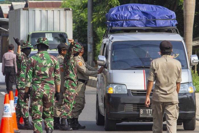 Petugas gabungan mengarahkan pemudik roda empat dari arah Bekasi menuju Karawang untuk berputar arah di Perbatasan Karawang - Bekasi, Jawa Barat, Jumat (24/4/2020). Penyekatan akses transportasi di perbatasan tersebut sebagai tindak lanjut kebijakan larangan mudik yang berlaku bagi kendaraan pribadi, angkutan umum dan motor kecuali mobil pemadam kebakaran, angkutan logistik dan kebutuhan pokok serta ambulan. ANTARA FOTO/M Ibnu Chazar/pras.