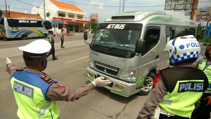 Petugas kepolisian memerintahkan mobil  travel untuk memutar kembali ke arah Jakarta saat penyekatan di jalur Pantura, Tegal, Jawa Tengah, Senin (27/4/2020). Penyekatan kendaraan pemudik oleh Polres Tegal Kota itu dilakukan menyusul adanya larangan mudik oleh Pemerintah guna mencegah penyebaran COVID-19. ANTARA FOTO/Oky Lukmansyah/hp.