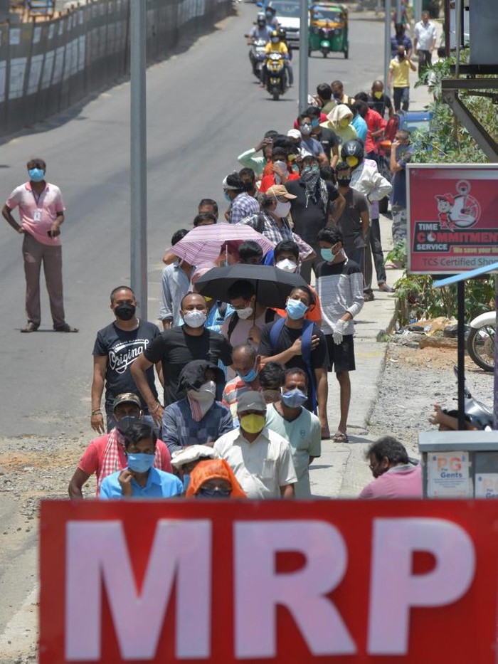 People queue to buy alcohol outside a Maximum Retail Price (MRP) liquor store after the government eased a nationwide lockdown imposed as a preventive measure against the COVID-19 coronavirus, in Bangalore on May 4, 2020. (Photo by Manjunath Kiran / AFP)