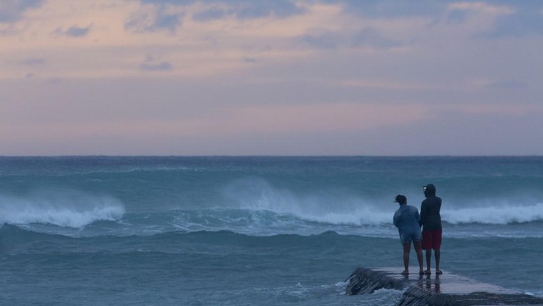 US-OAHU-REMAINS-UNSCATHED-BY-HURRICANE-LANE HONOLULU, HI - AUGUST 24: Warnings of dangerous rip currents does not deter people from walking the wave swept break wall at the East end of Waikiki beach to take selfies with the sunset and stormy seas caused by Hurricane Lane on August 24, 2018. Kat Wade/Getty Images/AFP