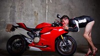 Waduh seorang pria mengikuti pose cium motor, lengkap dengan jaket kulit dan celana sangat pendek. Foto: Motocorsa
