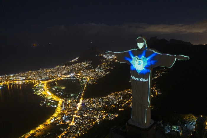 Kini, Patung Yesus di Brasil Bermandikan Cahaya dan Bermasker Patung Kristus Sang Penebus Rio menyala seolah-olah mengenakan topeng pelindung di tengah pandemi Coronavirus baru, di Rio de Janeiro, Brasil, Minggu (3/5/2020). Pesan