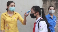 Setiap pelajar yang akan masuk ke ruang kelas diperiksa terlebih dahulu suhu tubuhnya oleh sang guru.