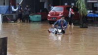 Seorang pengendara motor berusaha menyeberangi banjir yang menrendam motornya. Banjir ini juga merendam beberapa pemukiman dan memutus lalu lintas di kawasan tersebut. Hanya truk-truk besar yang dalam menerobos banjir.