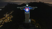Patung Christ the Redeemer (Kristus Sang Penebus) menjadi salah satu ikon Brasil. Berlokasi di puncak Gunung Corcovado, patung ini bisa terlihat dari seluruh sudut kota Rio de Janeiro, Brasil. Dalam momen bersejarah, Patung Kristus Sang Penebus kerap diberi efek visual, seperti saat Brasil menang Piala Dunia 2014 lalu. Kini saat pandemi Corona, Patung Yesus bermasker dan bermandikan cahaya.