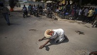 Seorang pengunjung gereja jatuh ke tanah dan berdoa di jalan dekat massa yang membakar ban dalam serangkaian krisis di Haiti (22/10/2019). Foto karya Rebecca Blackwell ini menjadi finalis kategori breaking news. AP Photo/Rebecca Blackwell.