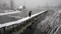 Penduduk Kashmir berjalan di jembatan setapak yang dipenuhi salju di danau Dal, Srinagar (india (13/12/2019). Foto seri ini meraih penghargaan untuk kategori Feature Photography.